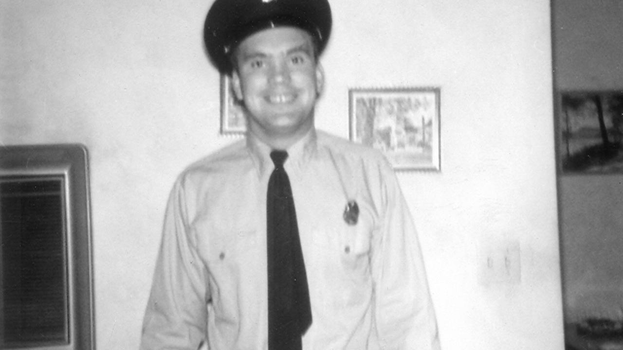 Jim Pfister in dress uniform beside a framed photograph, 1961.