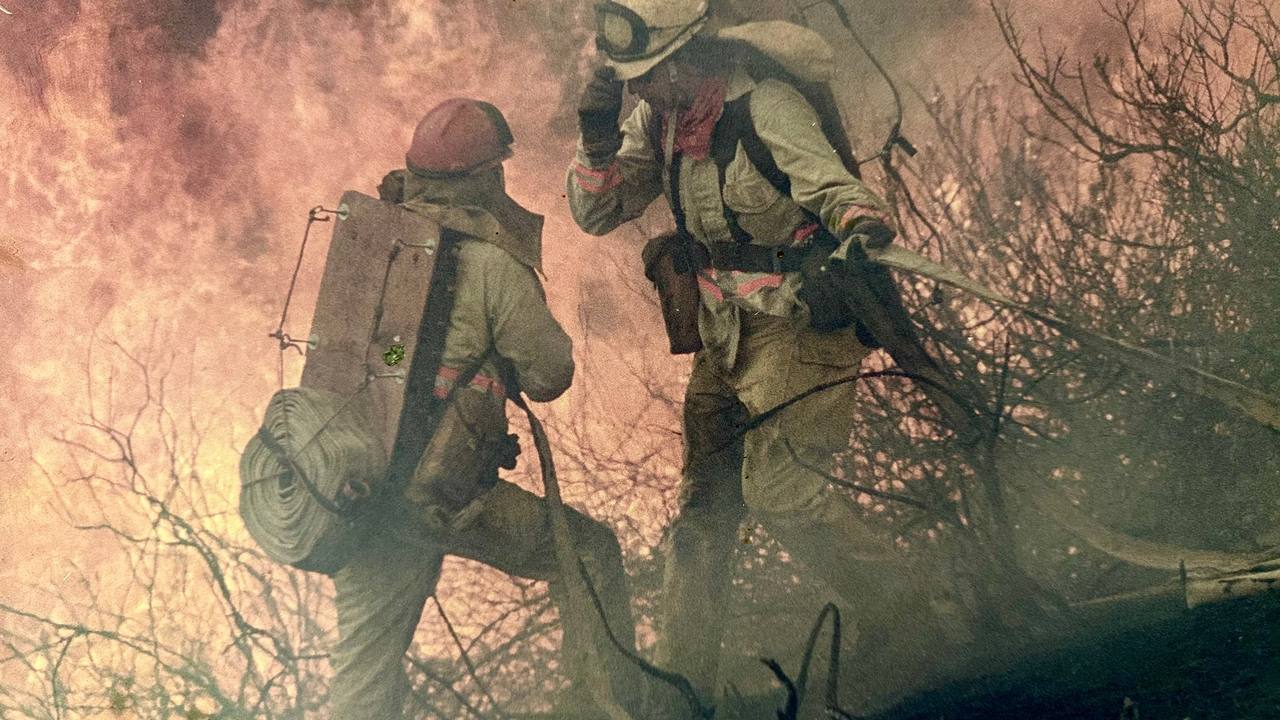 Two firefighters working a brush fire in heavy smoke.