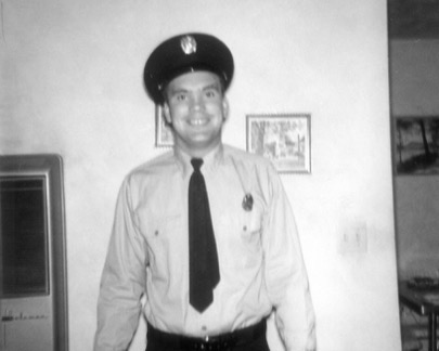 Jim Pfister in dress uniform beside a framed photograph, 1961.